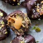 Cracked open peanut butter stuffed oozing from a chocolate coated date.