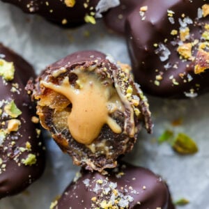 Cracked open peanut butter stuffed oozing from a chocolate coated date.