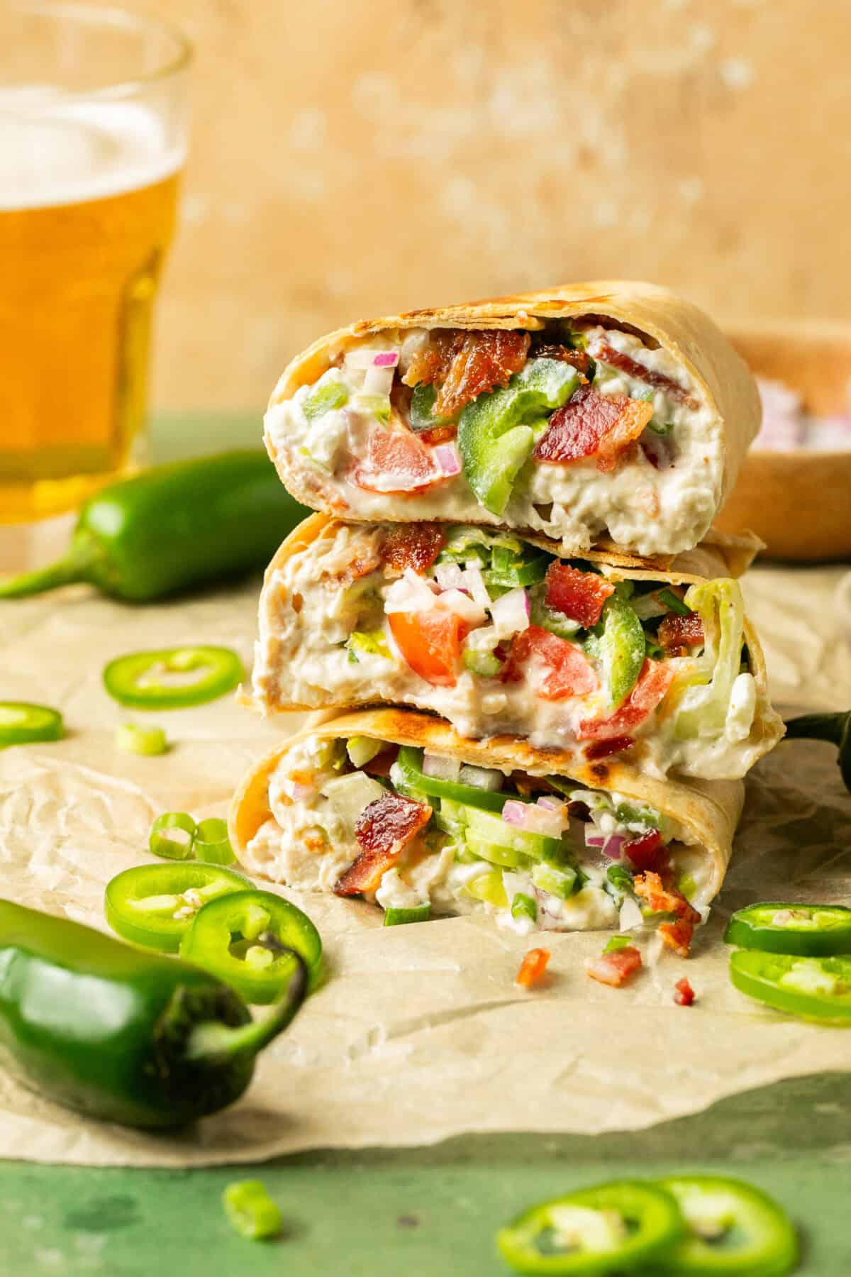 Three stacked jalapeno popper shredded chicken wraps with the inside showing.