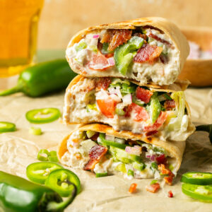 Three stacked jalapeno popper shredded chicken wraps with the inside showing.