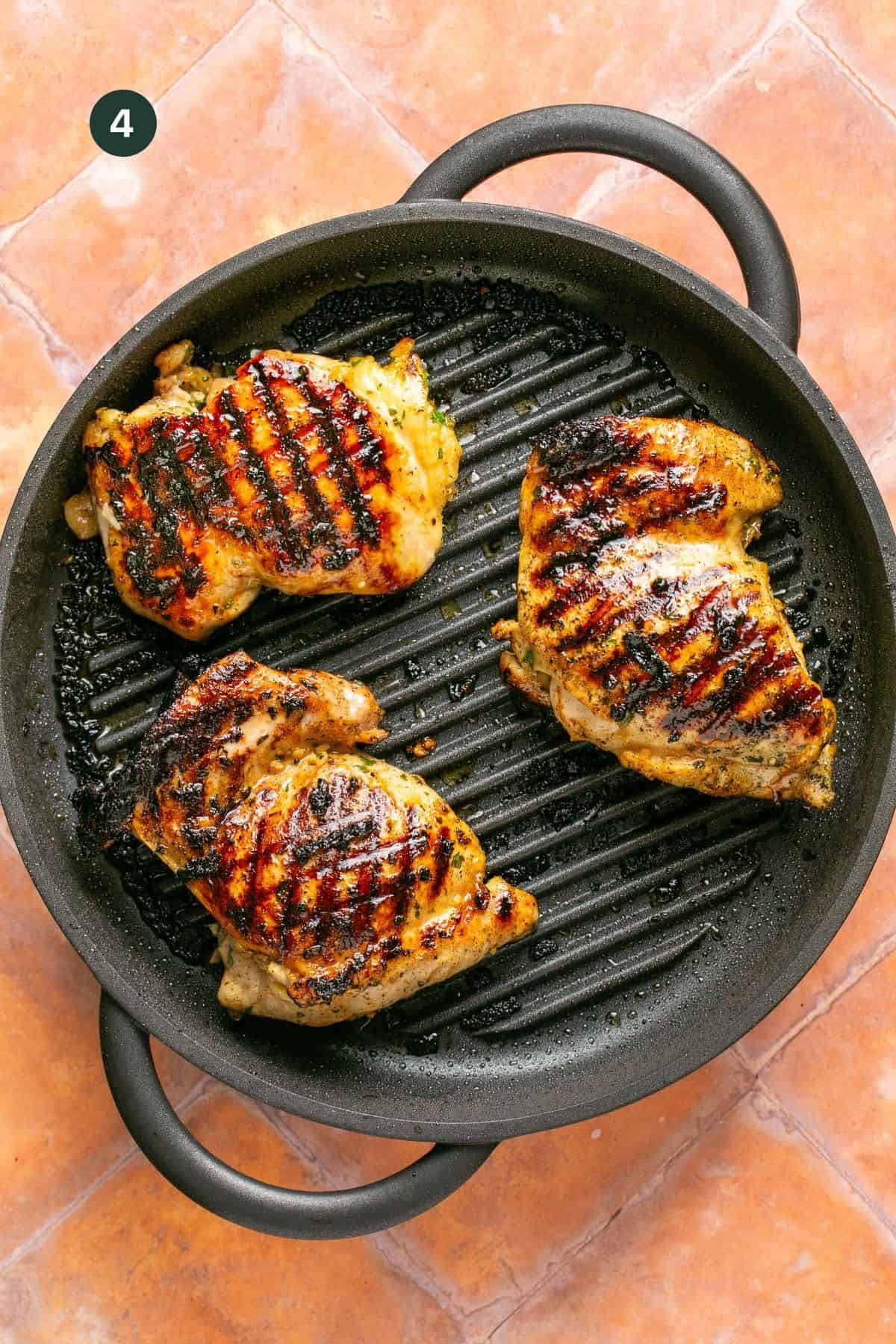 Browned and cooked marinated chicken thighs on a grill pan.