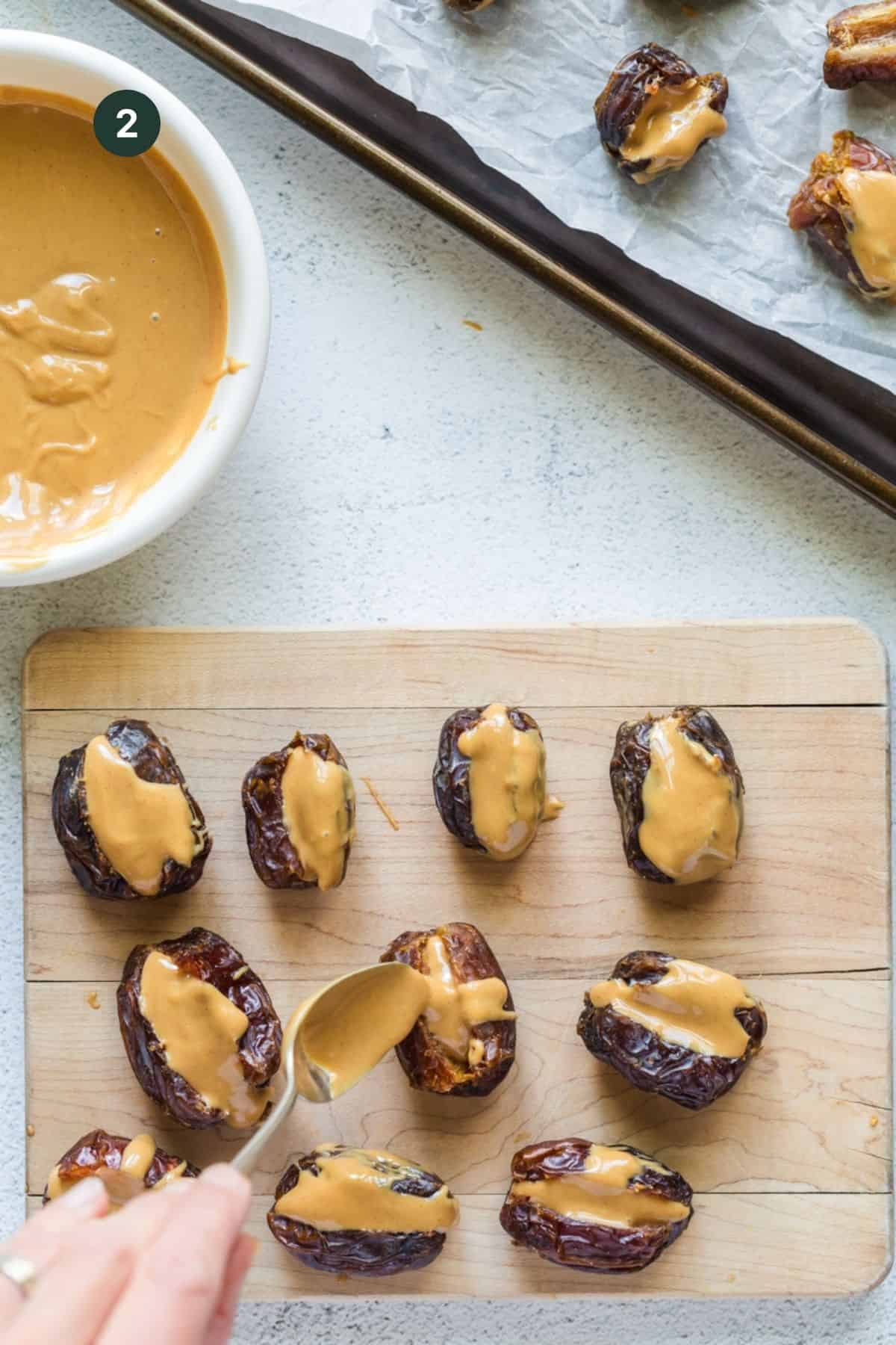 Filling the date inside with peanut butter on a wooden cutting board with a spoon. 