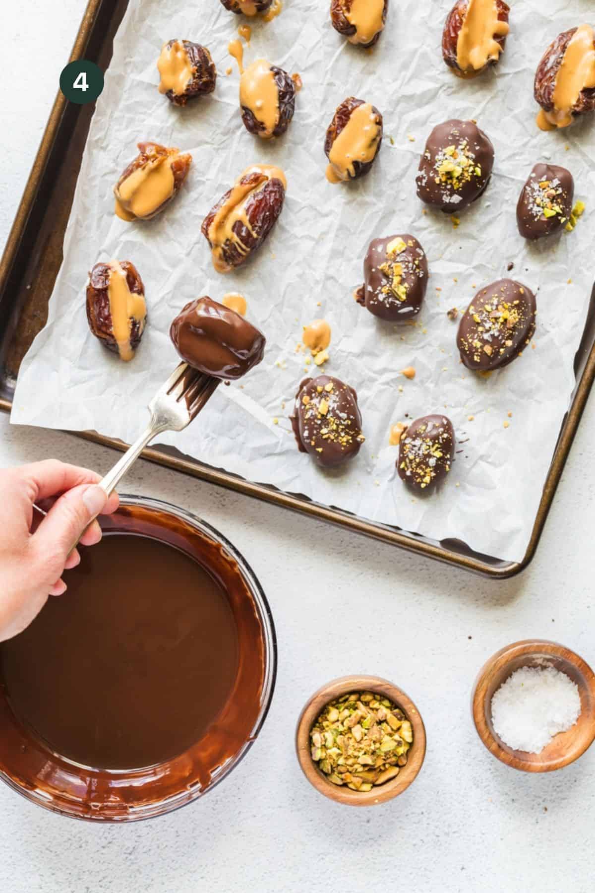 Fork with a chocolate covered date on it placing back on a baking sheet full of dates.