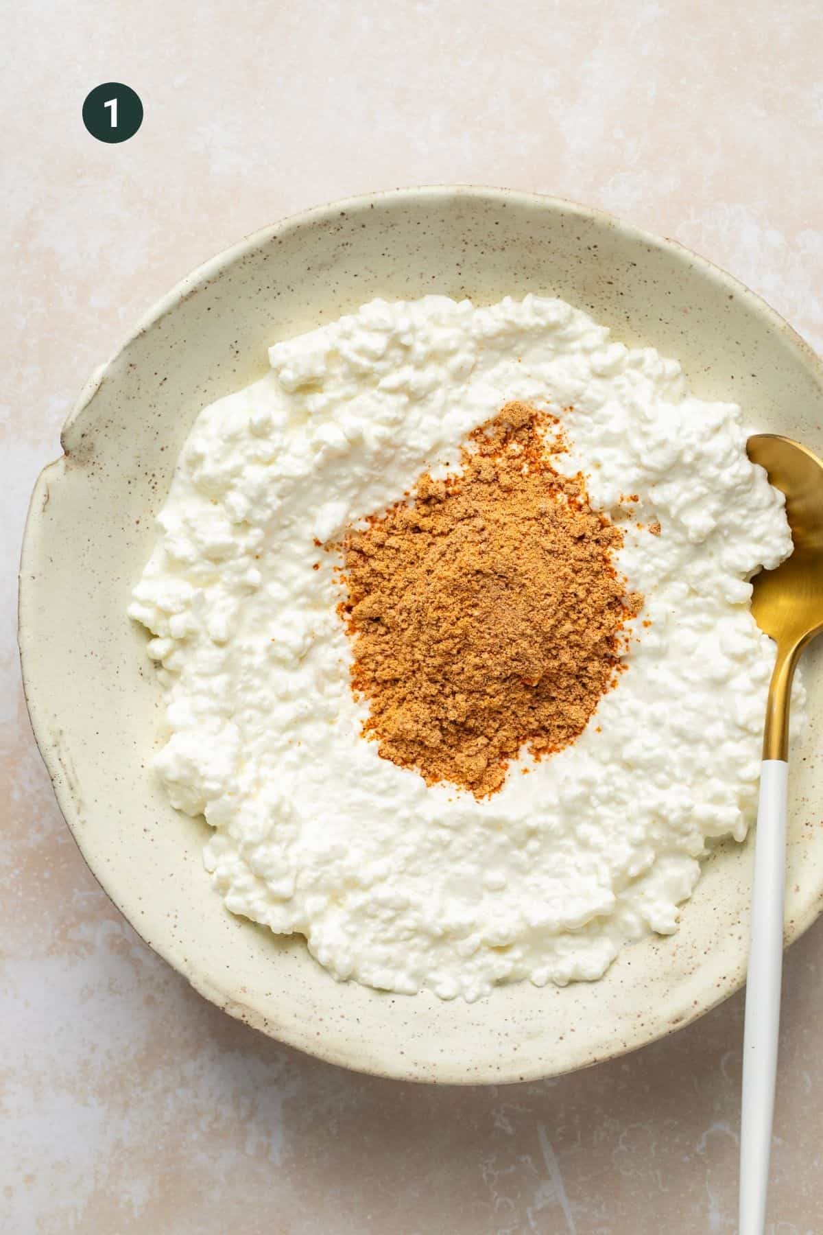 Cottage cheese and taco seasoning in a bowl with a spoon to mix.