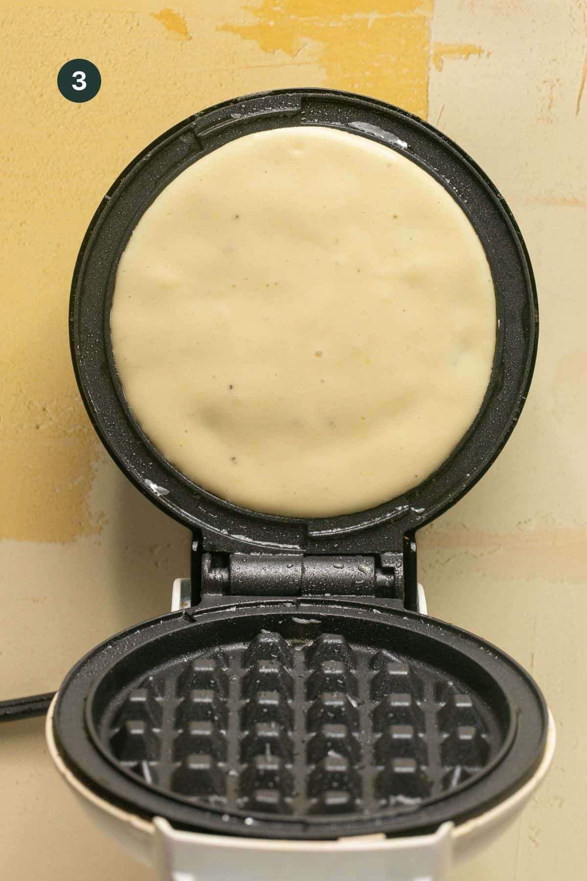 Waffle batter added to a hot small waffle maker.