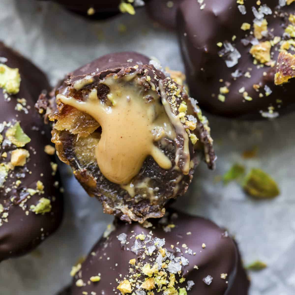 Cracked open peanut butter stuffed oozing from a chocolate coated date.