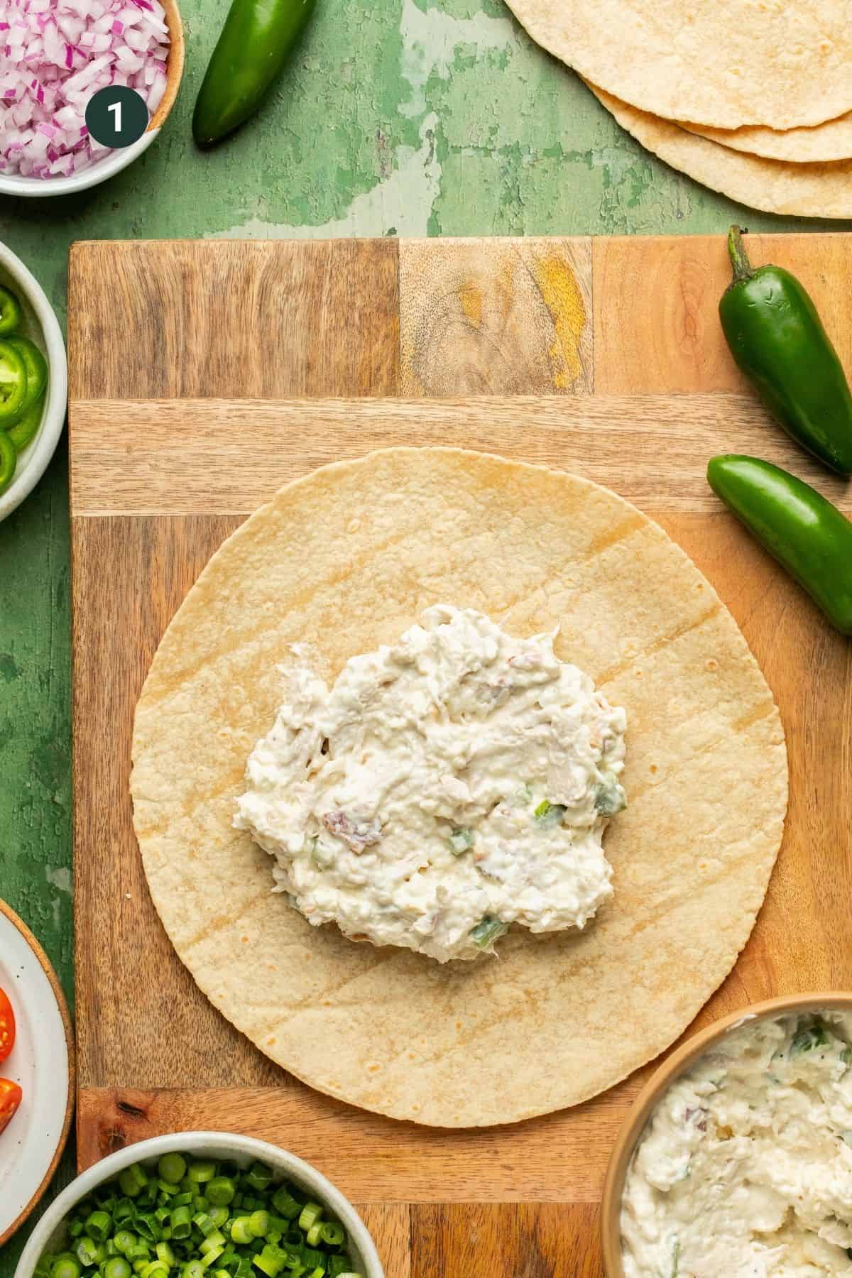 Dip on a tortilla with toppings spread around.