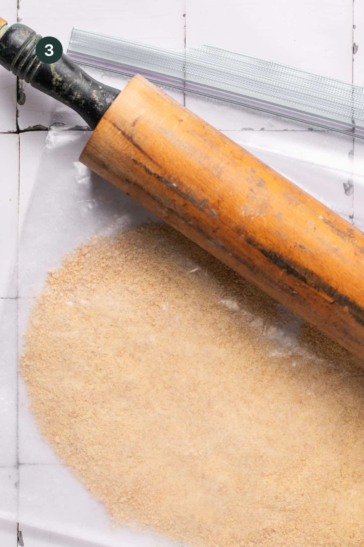 Graham crackers crushed in a ziplock with a rolling pin on top.