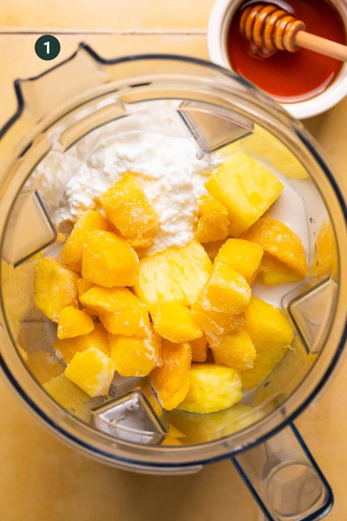 Cottage cheese, vanilla bean paste, almond milk, protein powder, fresh pineapple, honey and frozen mango in the base of a blender to mix.