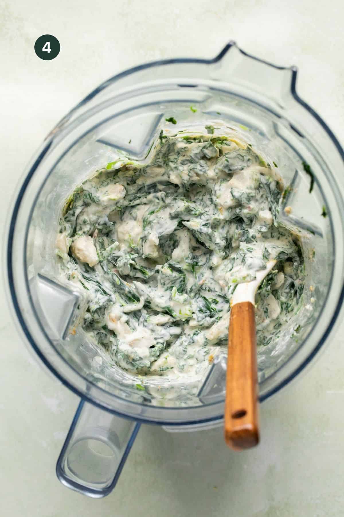 Fully combined and mixed cottage cheese spinach dip in a blender with a rubber spatula. 