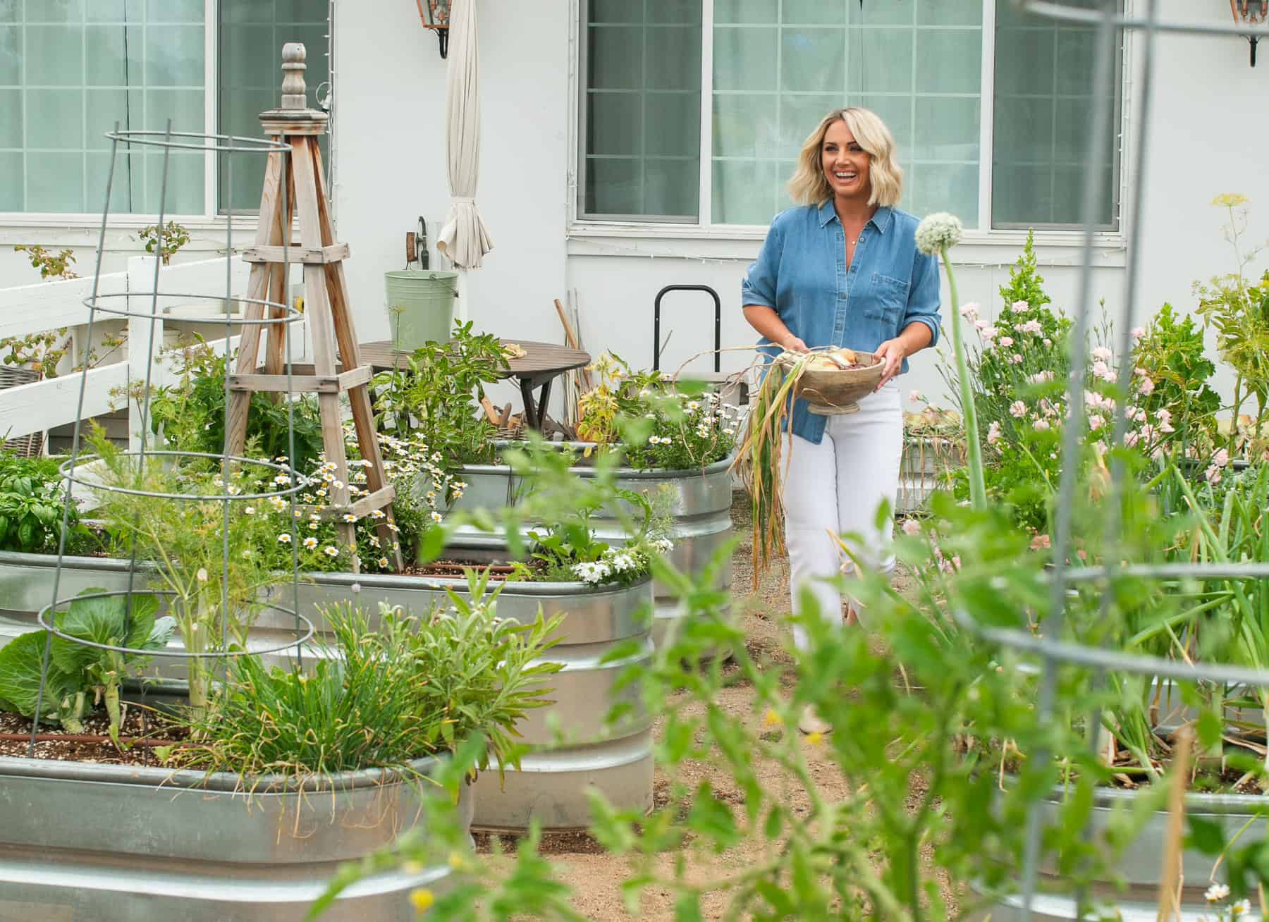 Danielle walking through a garden with a bowl of fresh vegetables.