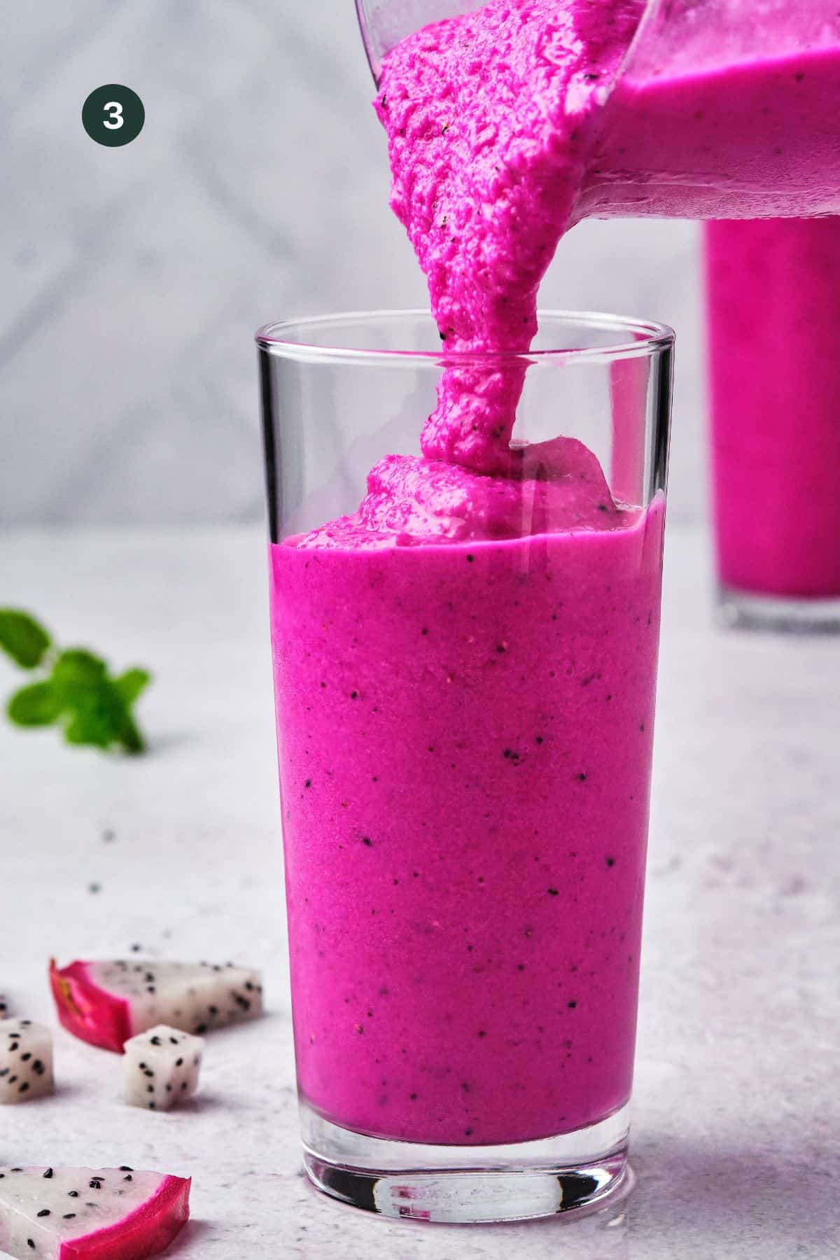 Bright and vibrant smoothie being poured in a tall glass.