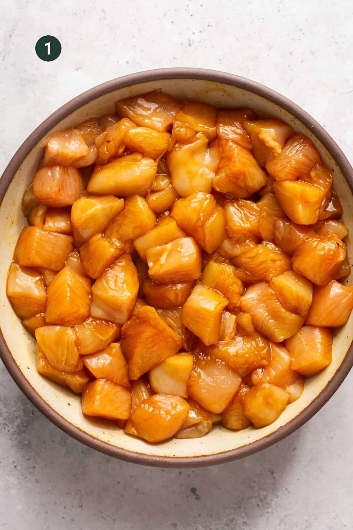 Marinated cubed chicken breast in a pan.