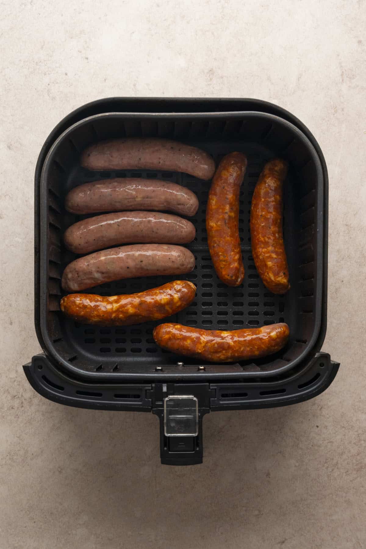 Chicken sausages in the base of the air fryer basket.