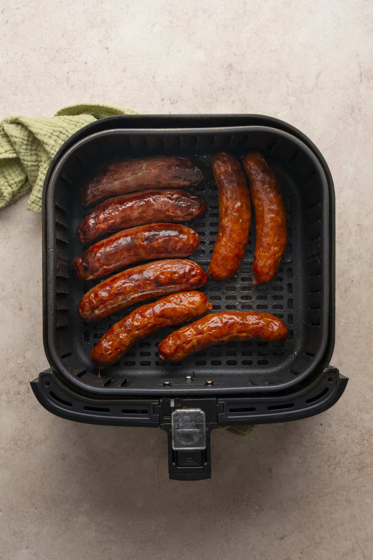 Air fried and browned chicken sausages in the base of a air fryer basket.