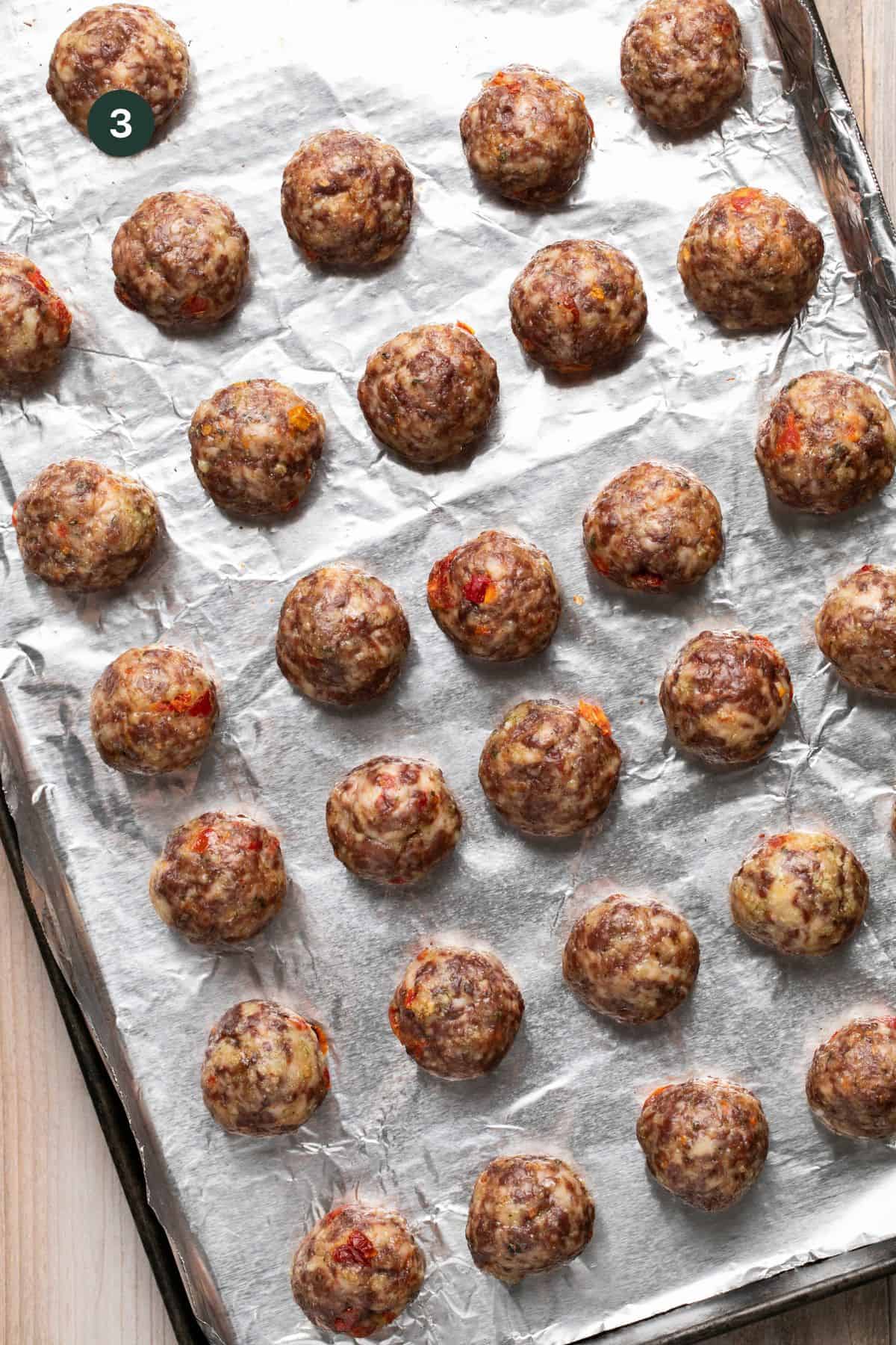 Fully baked and browned meatballs on the foiled lined sheet. 