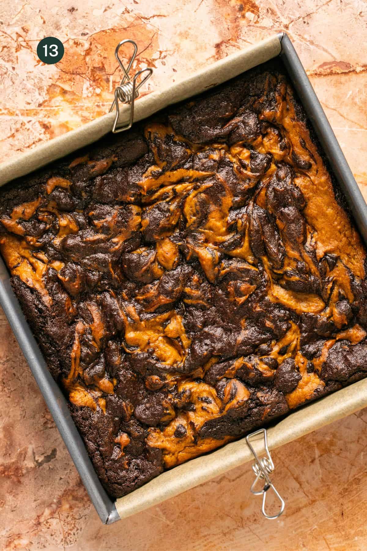 Fully baked and browned pumpkin and chocolate swirled top brownies in a baking pan.