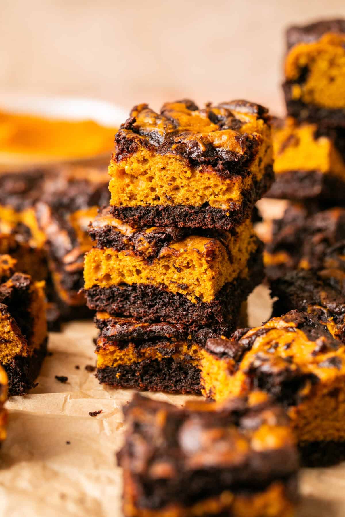 Chocolate and pumpkin layered brownies stacked on top of one another cooling. 