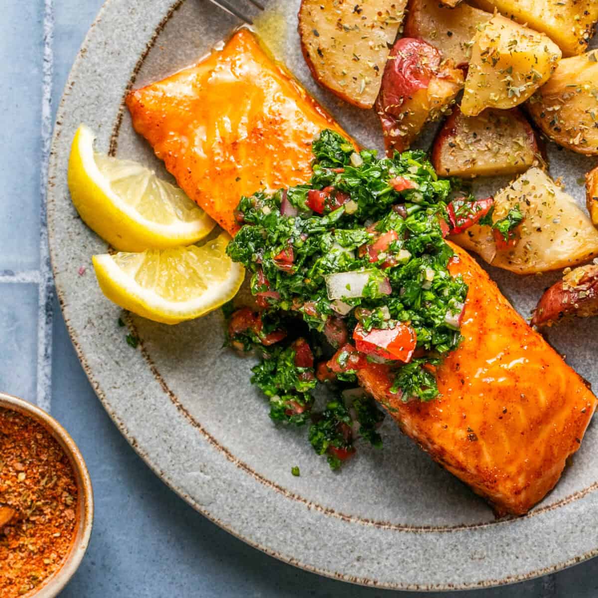 Salmon topped with chimichurri sauce and a side of roasted potatoes.