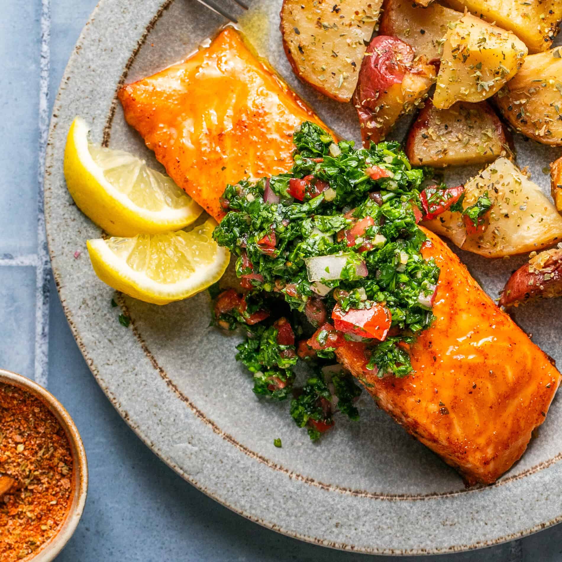 Salmon topped with chimichurri sauce and a side of roasted potatoes.