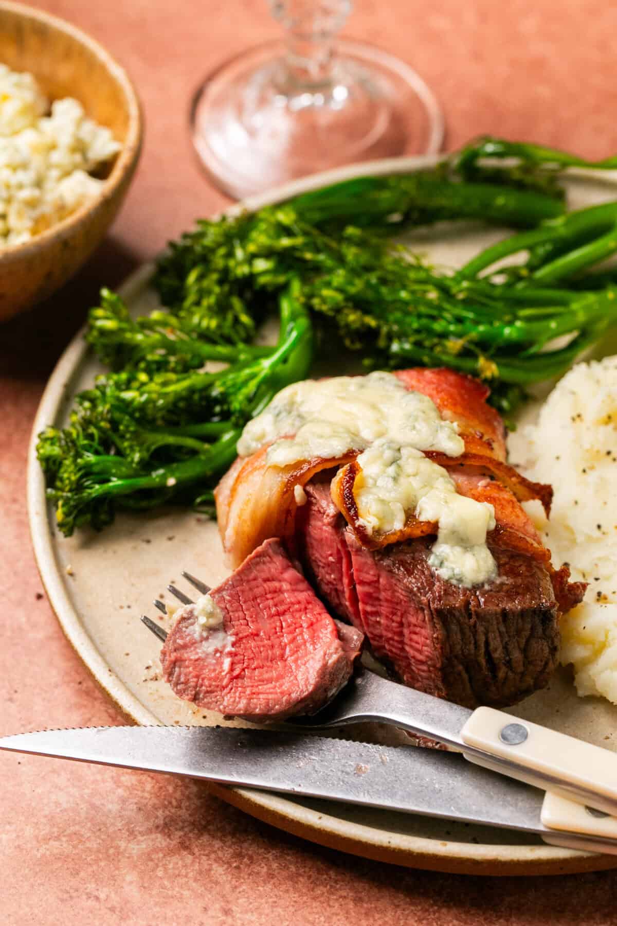 Perfectly cooked filet wrapped in bacon and topped with melted gorgonzola with a side of mashed potatoes and broccoli.