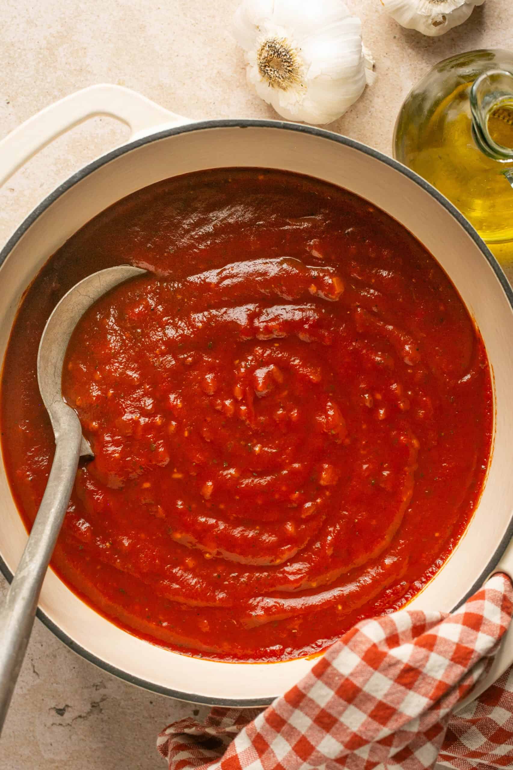 Big pot of tomato pasta sauce with a spoon for serving.