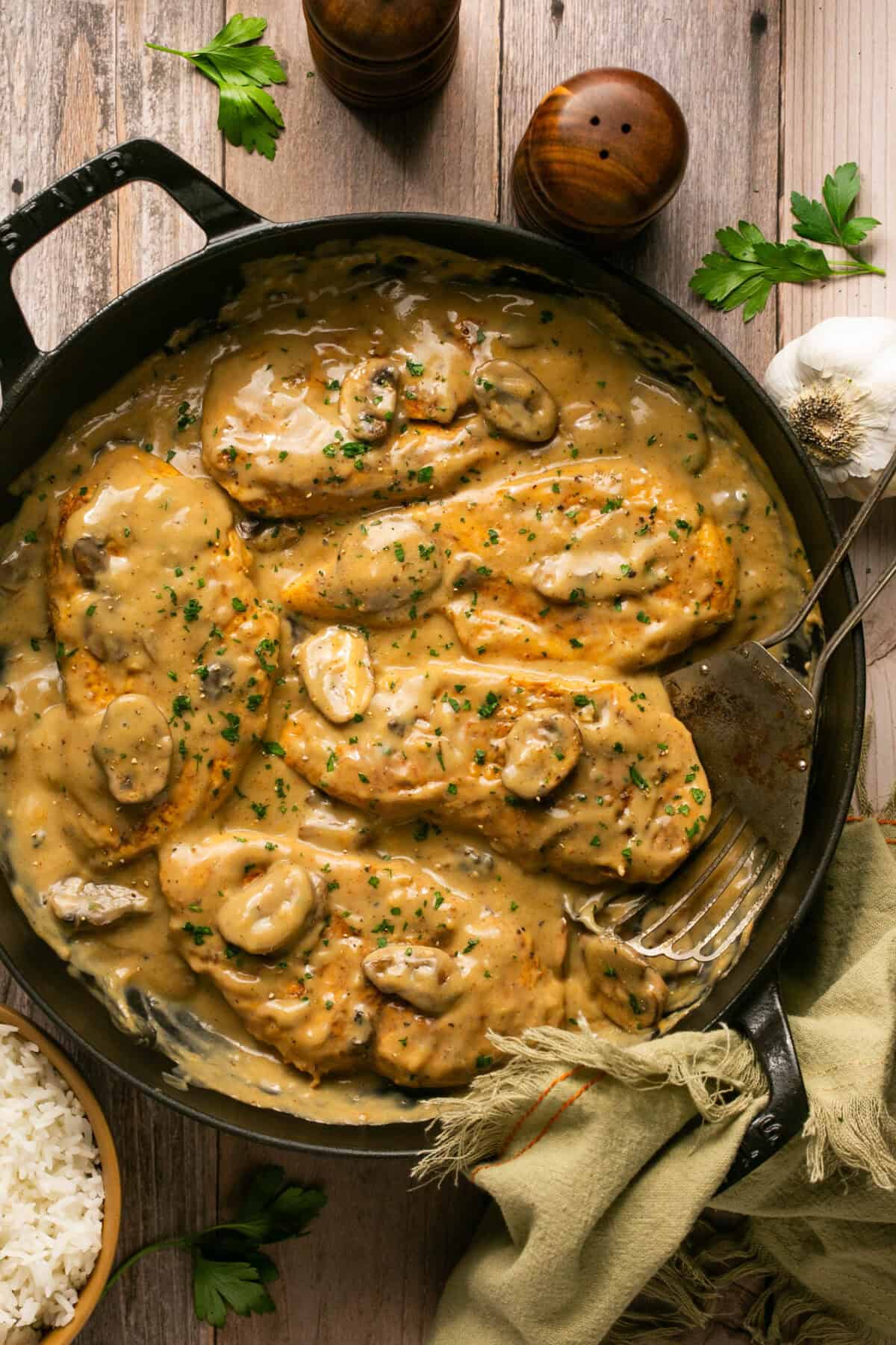 Creamy mushroom sauce chicken in a skillet with a spatula for serving.