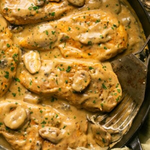 Creamy mushroom sauce chicken in a skillet with a spatula for serving.