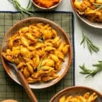 Pumpkin beef pasta plated on a placemat with a fork for eating with sprigs of fresh rosemary.