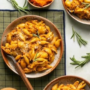 Pumpkin beef pasta plated on a placemat with a fork for eating with sprigs of fresh rosemary.