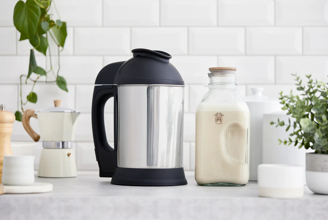 The Almond Cow machine on a modern counter with the milk jug full of milk.