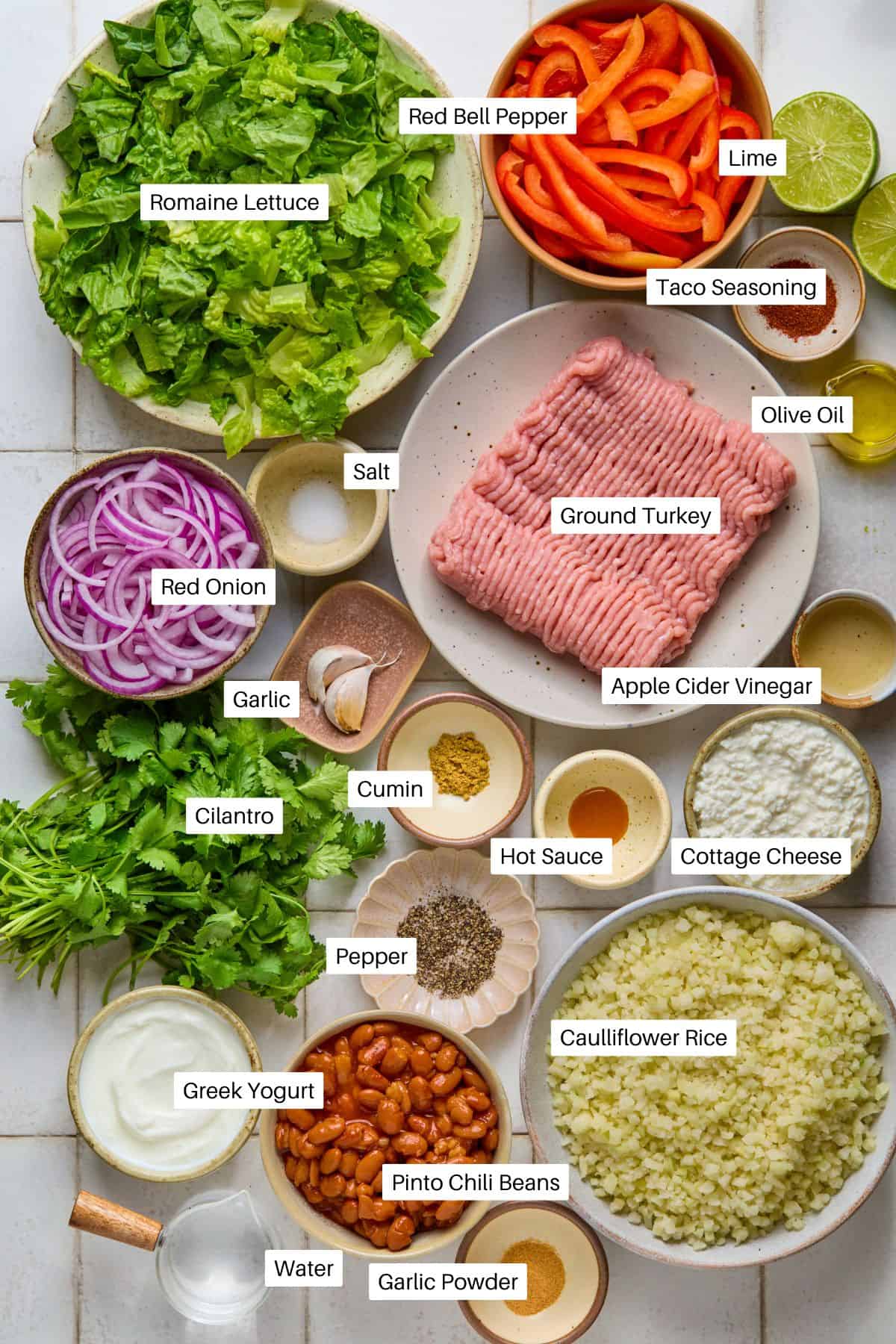 Ingredients for a delightful taco bowl recipe include romaine lettuce, red bell pepper, lime, and taco seasoning. Ground turkey and pinto chili beans are enhanced with olive oil, red onion, apple cider vinegar, salt, garlic, cottage cheese, cumin, and cilantro for a flavorful meal.