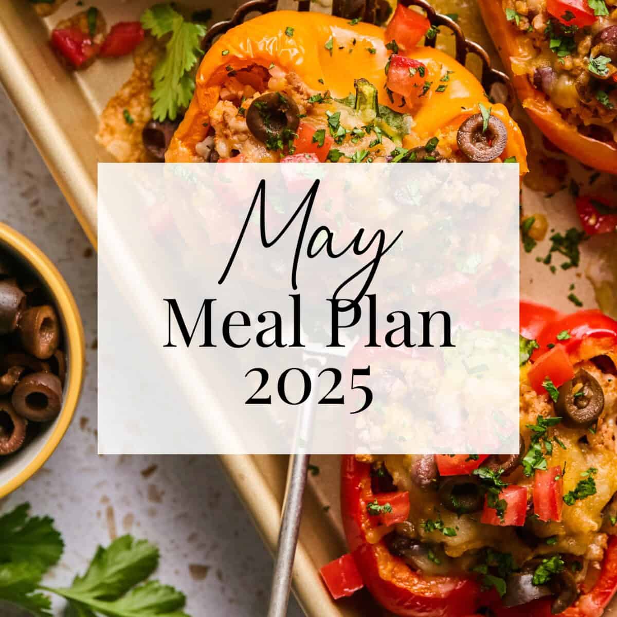 A tray of stuffed bell peppers with herbs and olives, next to a bowl of sliced black olives. Text overlay in the center reads: May Meal Plan 2025.