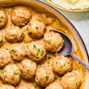 A bowl of meatballs and mashed potatoes topped with savory meatballs and gravy.