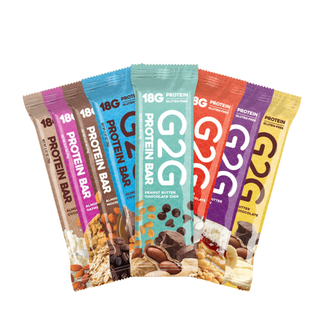 A variety of G2G Protein Bars in colorful wrappers are arranged in a fan shape, showcasing different flavors such as peanut butter chocolate chip, almond, coconut, and cashew.