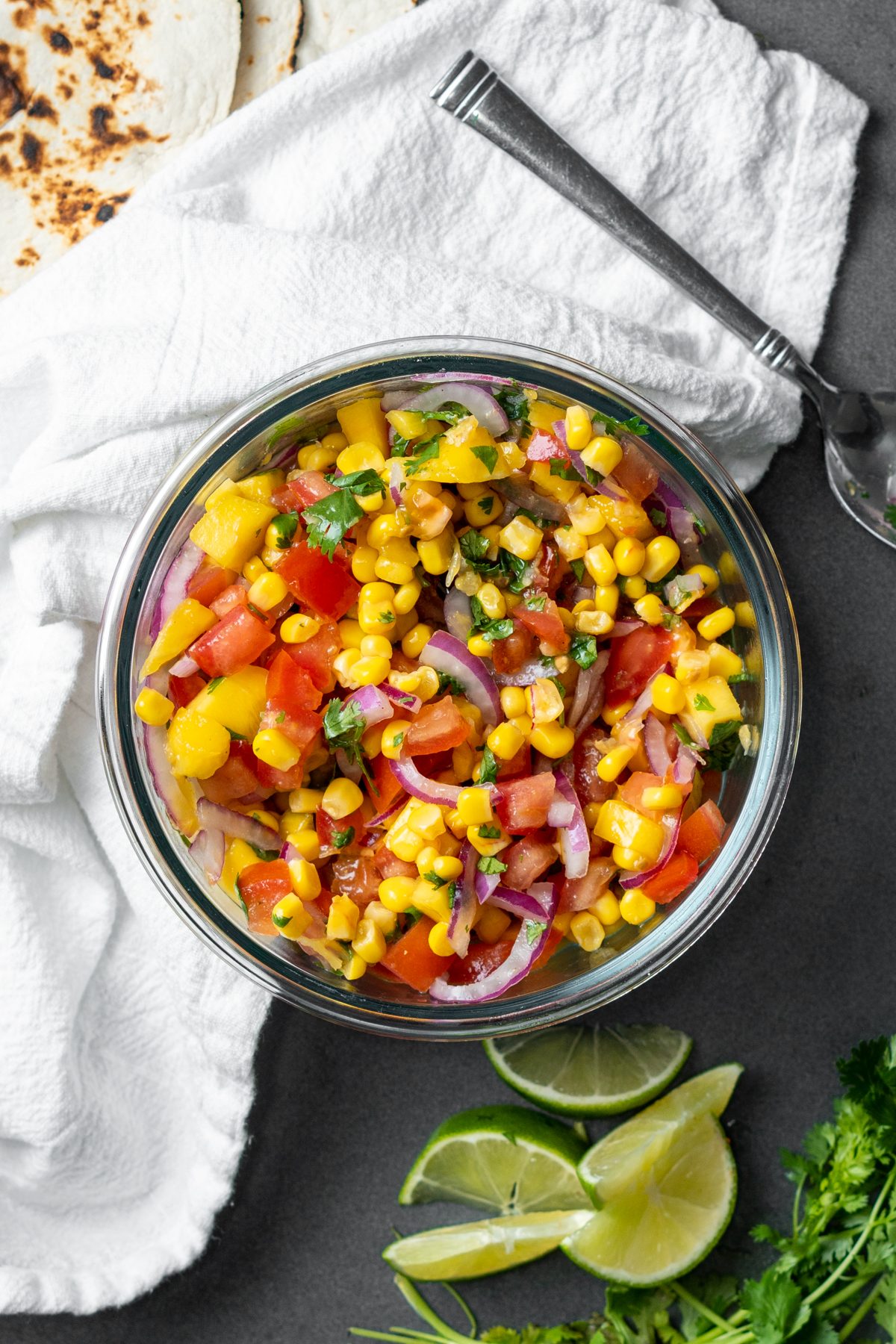 Colorful mango corn salsa with a white cloth napkin.