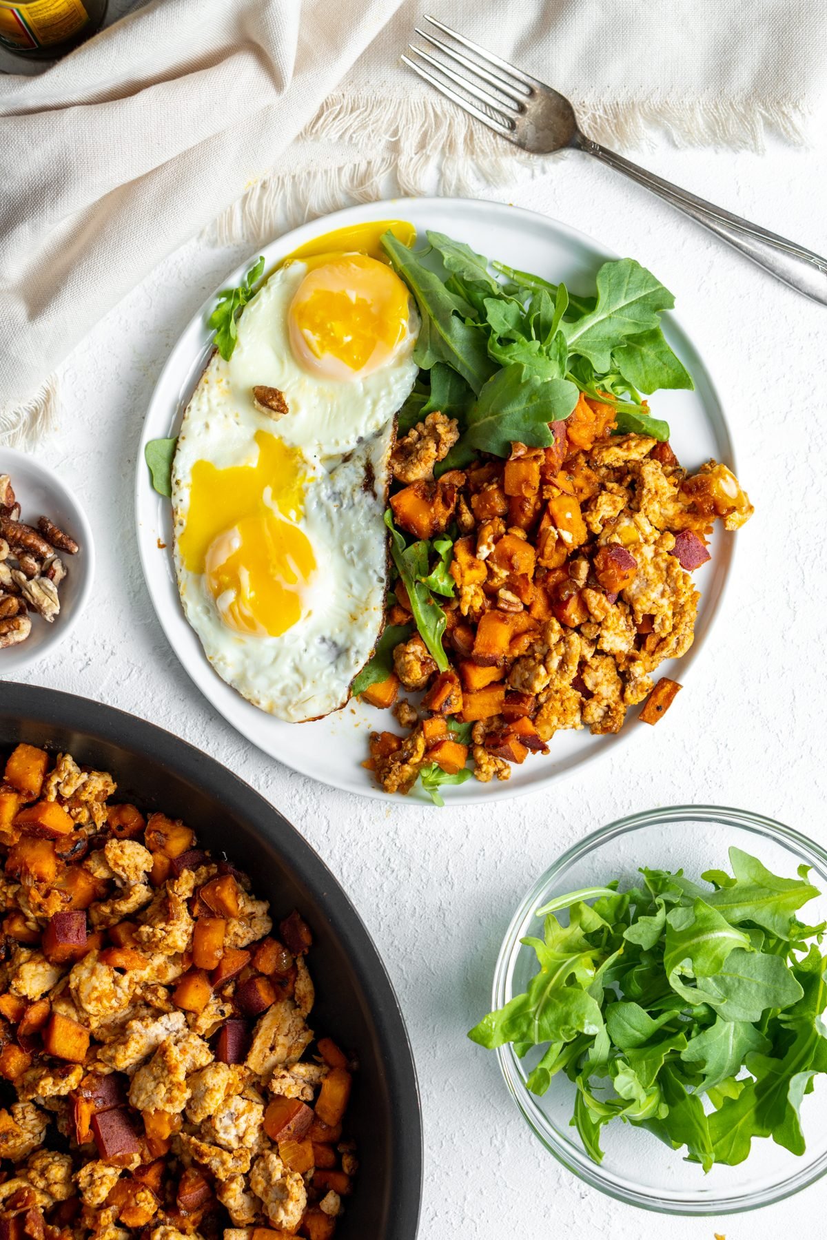 Turkey sweet potato hash on a plate with eggs and greens.