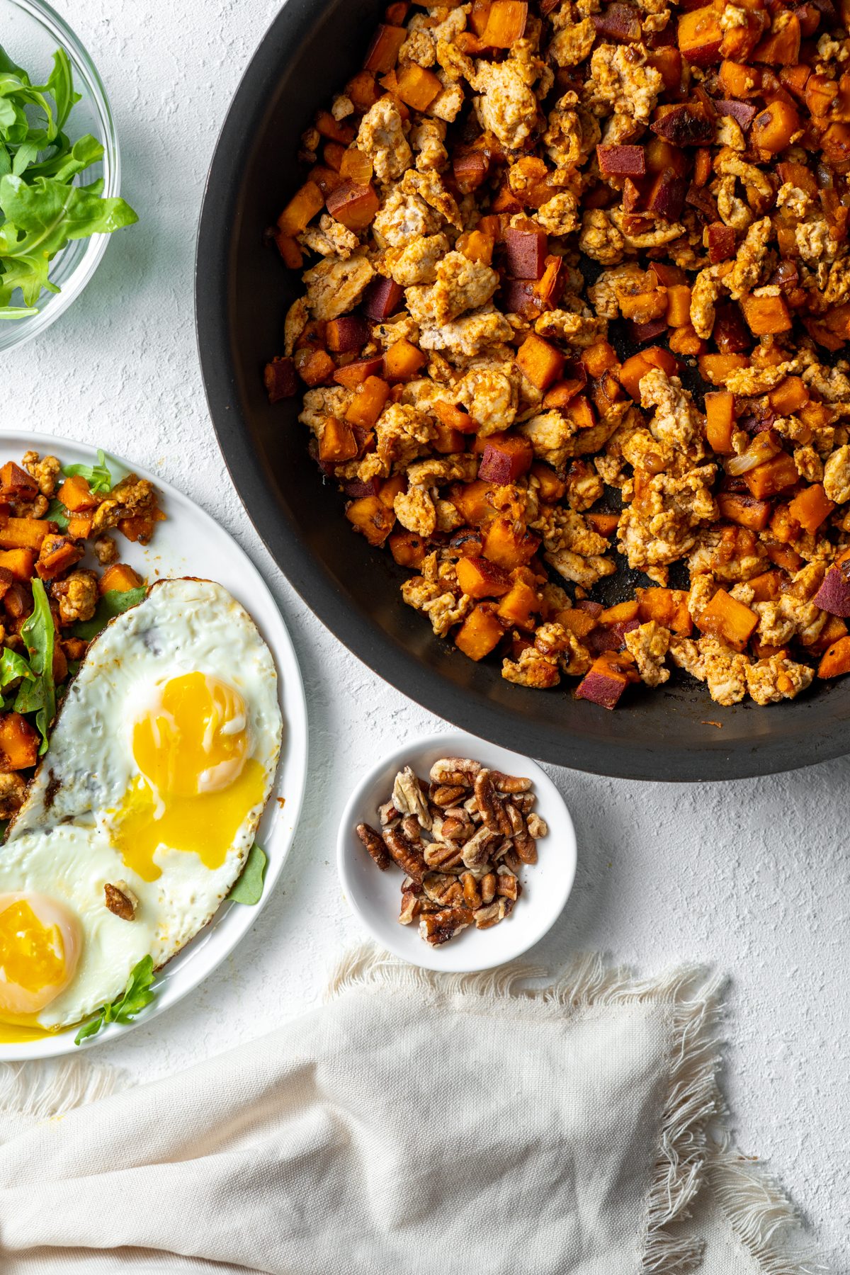 Plate with eggs next to a pan of turkey sweet potato hash.