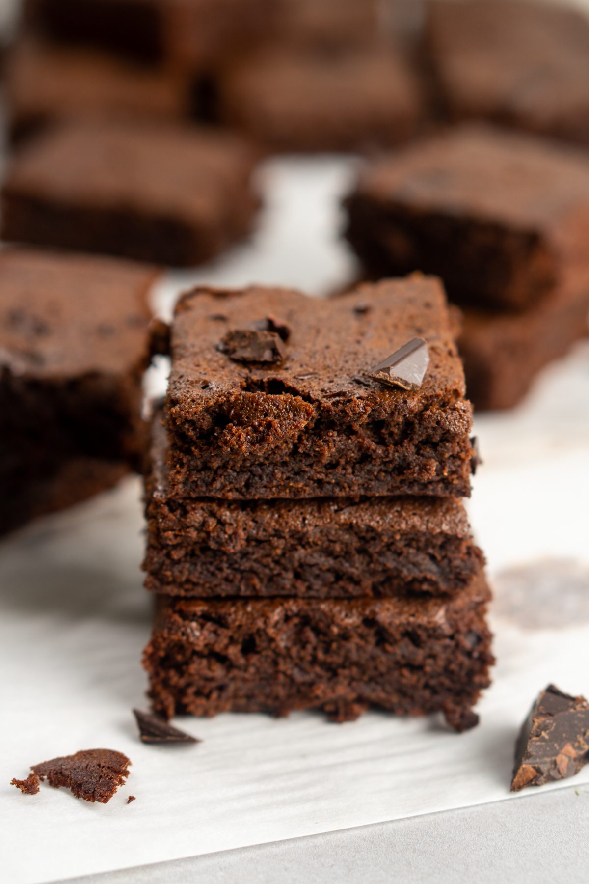 Mint chocolate brownies stacked on parchment paper.