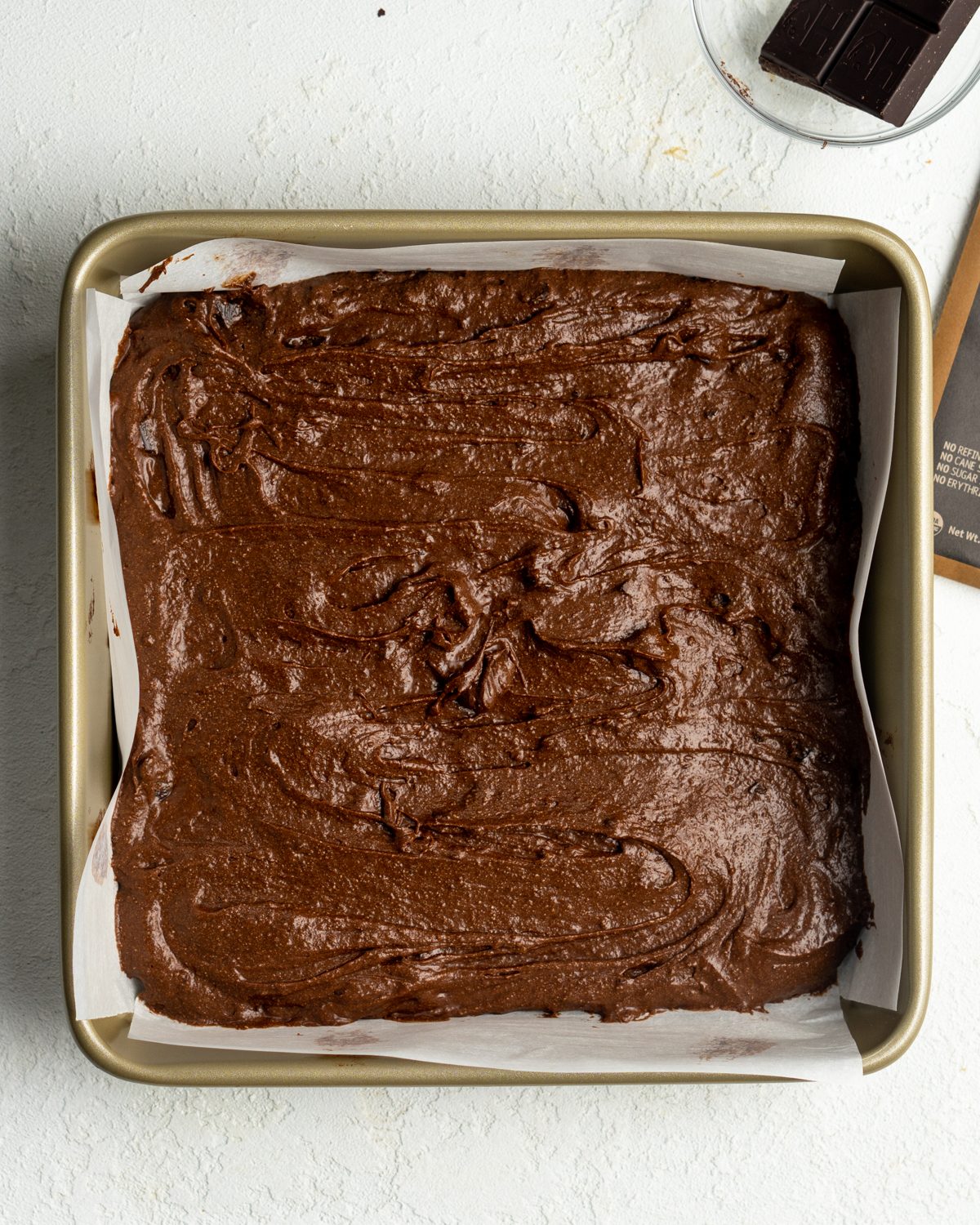 Brownie batter in a lined baking dish.