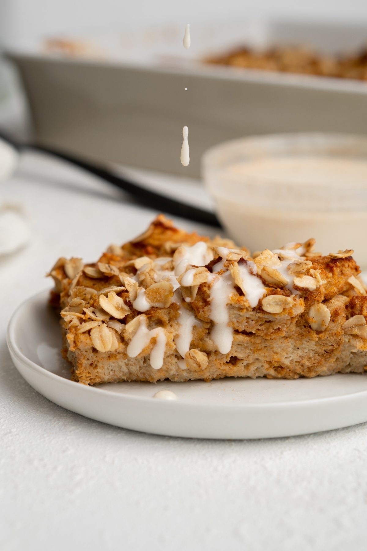 Drop of protein frosting falling onto a slice of pumpkin French toast casserole.