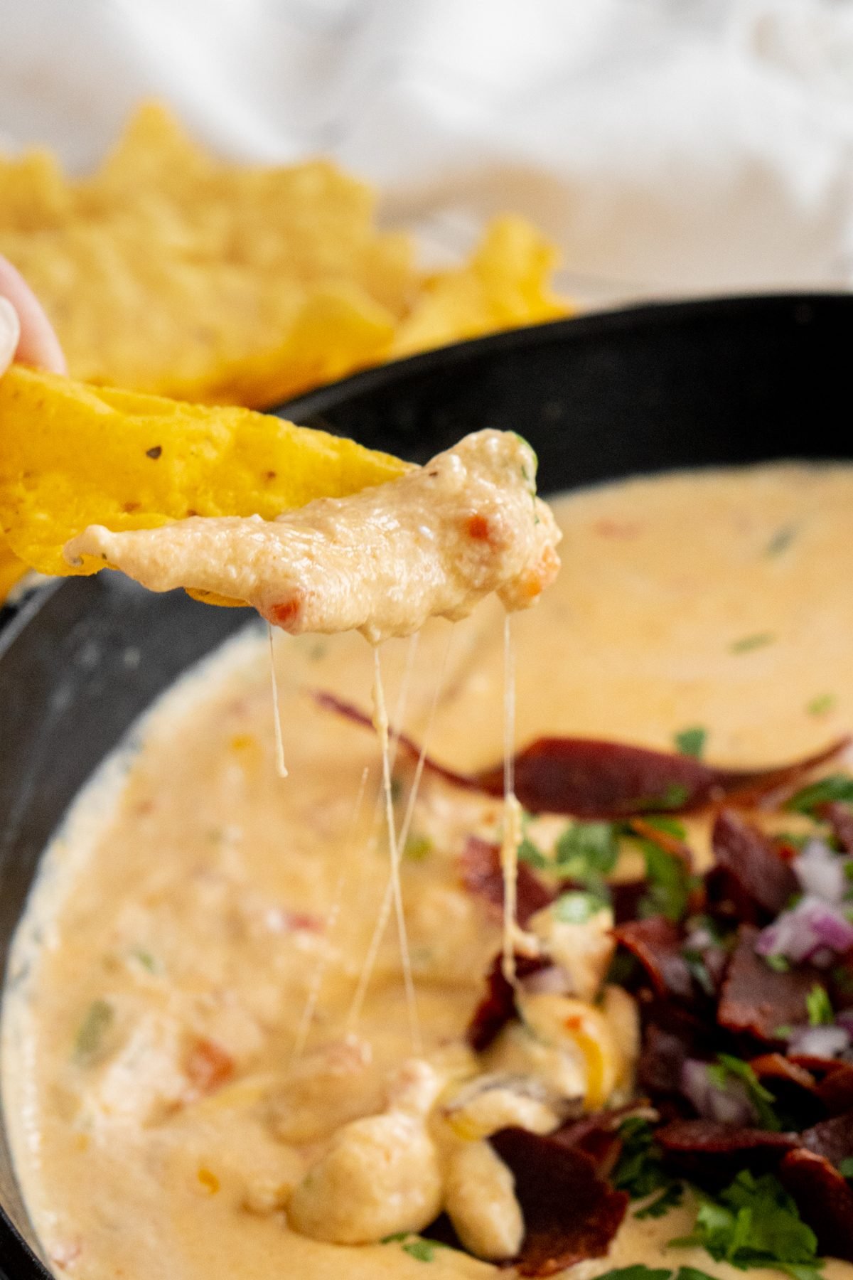 Chip scooping queso.