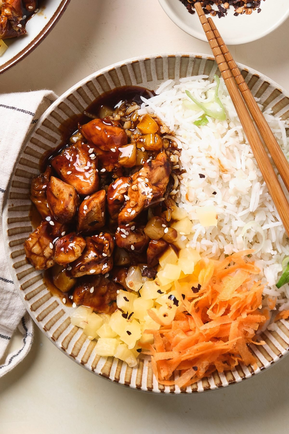 Bowl of chicken teriyaki, pineapple, carrots, and rice.