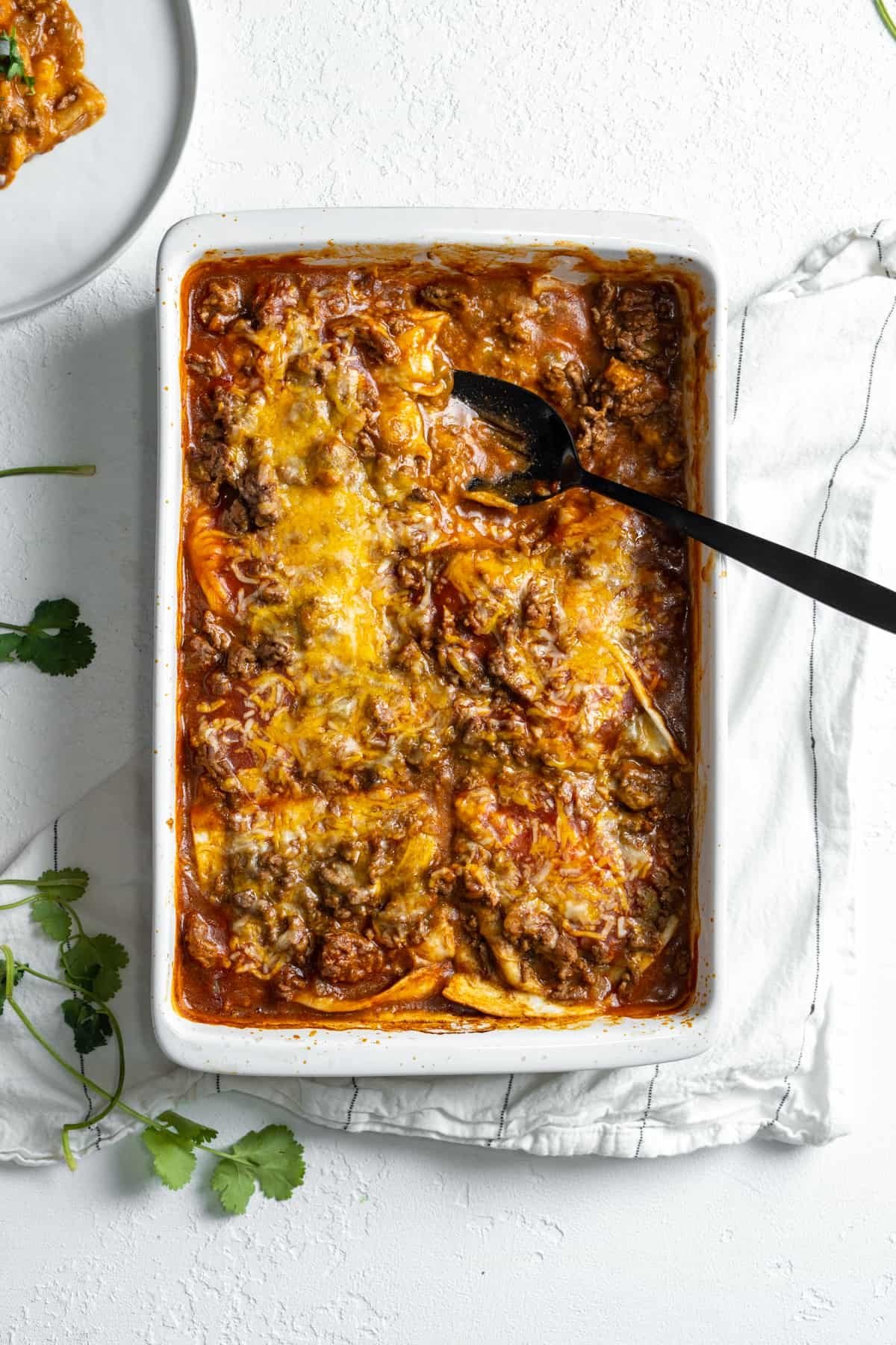 Serving spoon in a baking dish of lazy enchiladas.