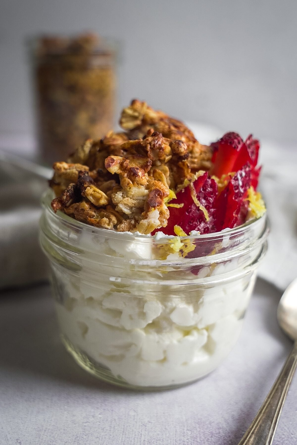 Lemon granola and strawberries atop a jar of yogurt.