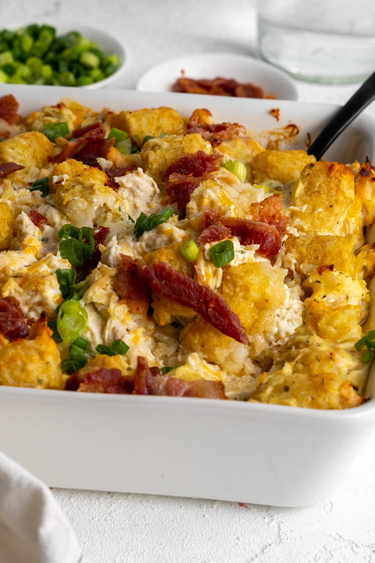 Tater tot casserole topped with bacon and green onion slices.