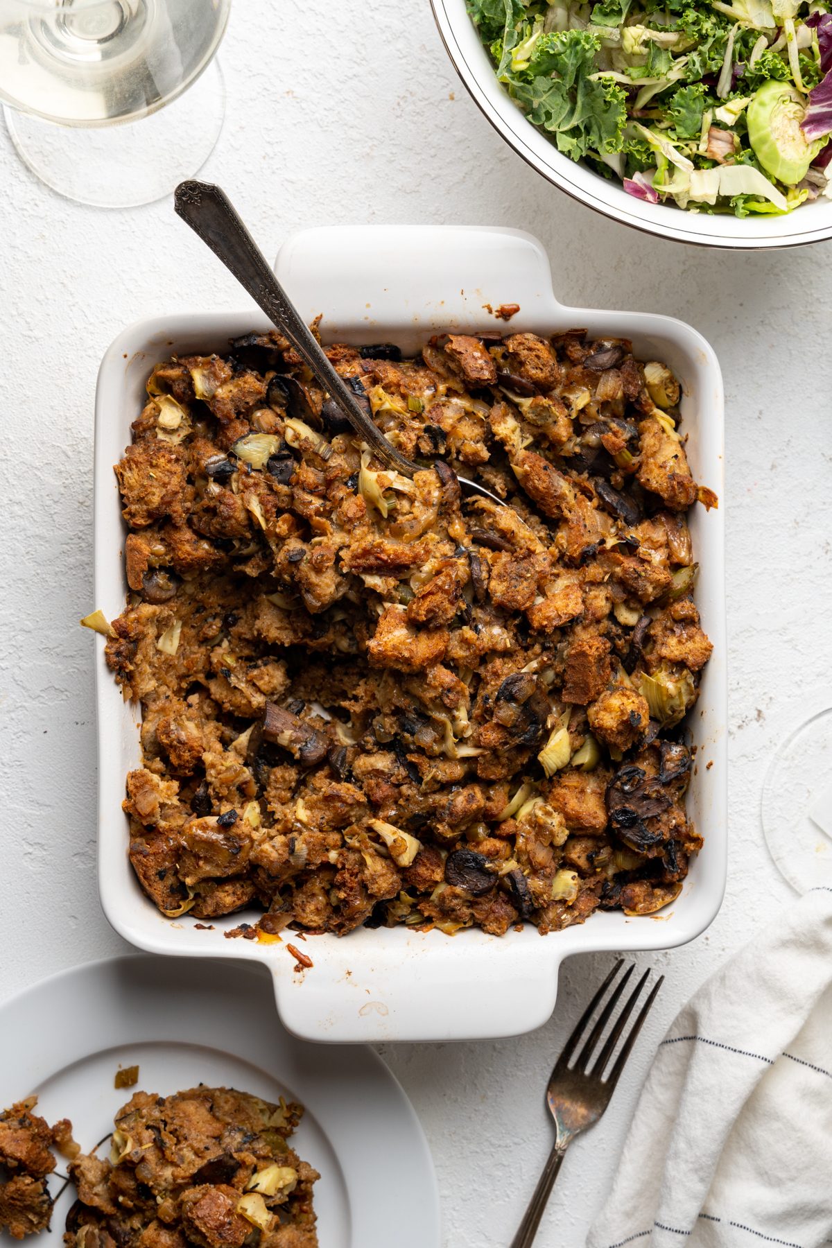 Holiday stuffing in a baking dish with a spoon.