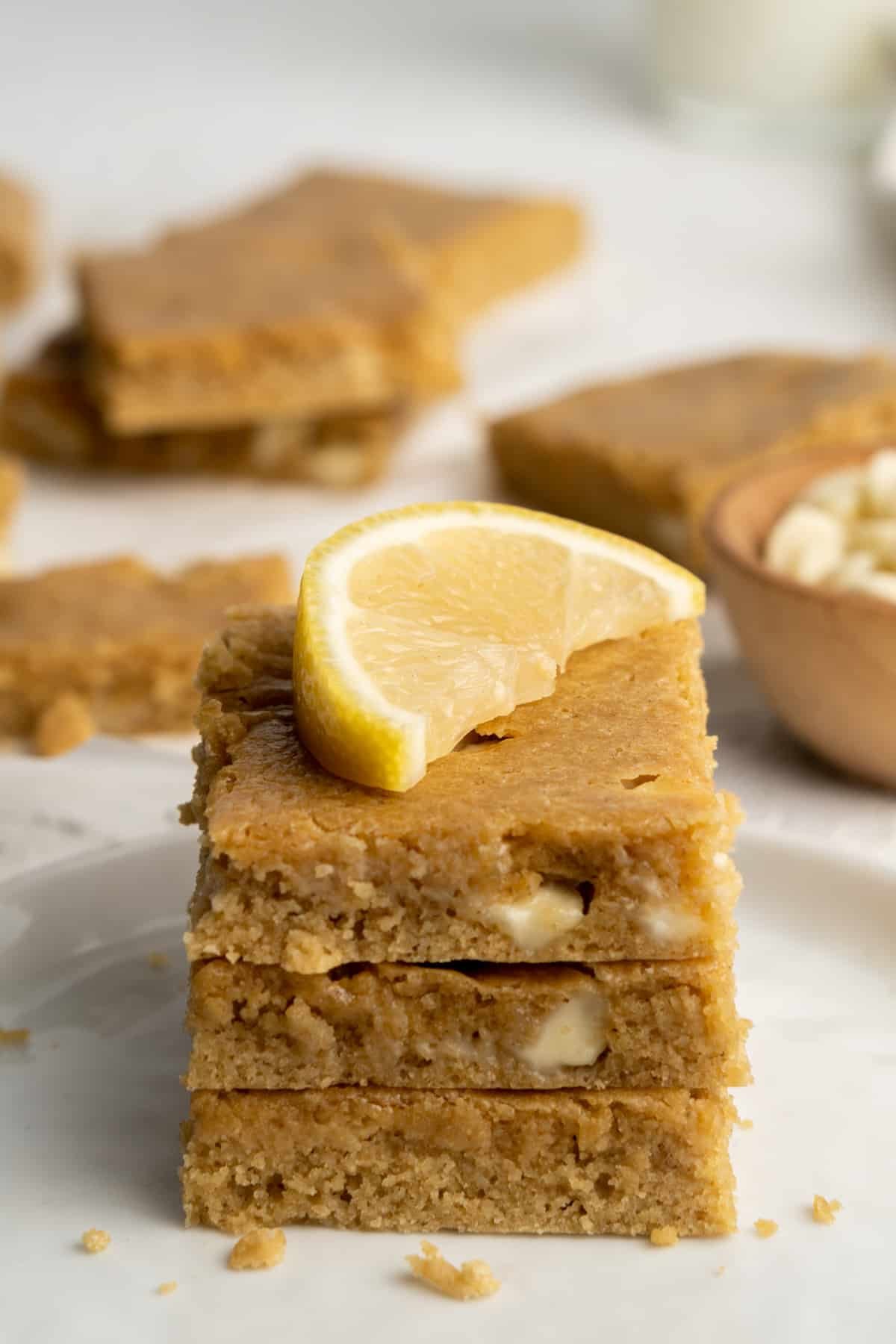 Stack of three lemon blondies topped with a lemon wedge.