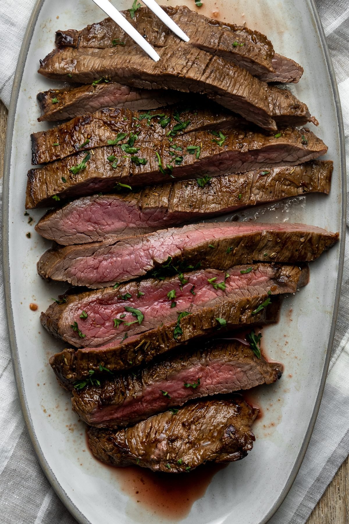 Medium rare strips of flank steak on a serving platter.
